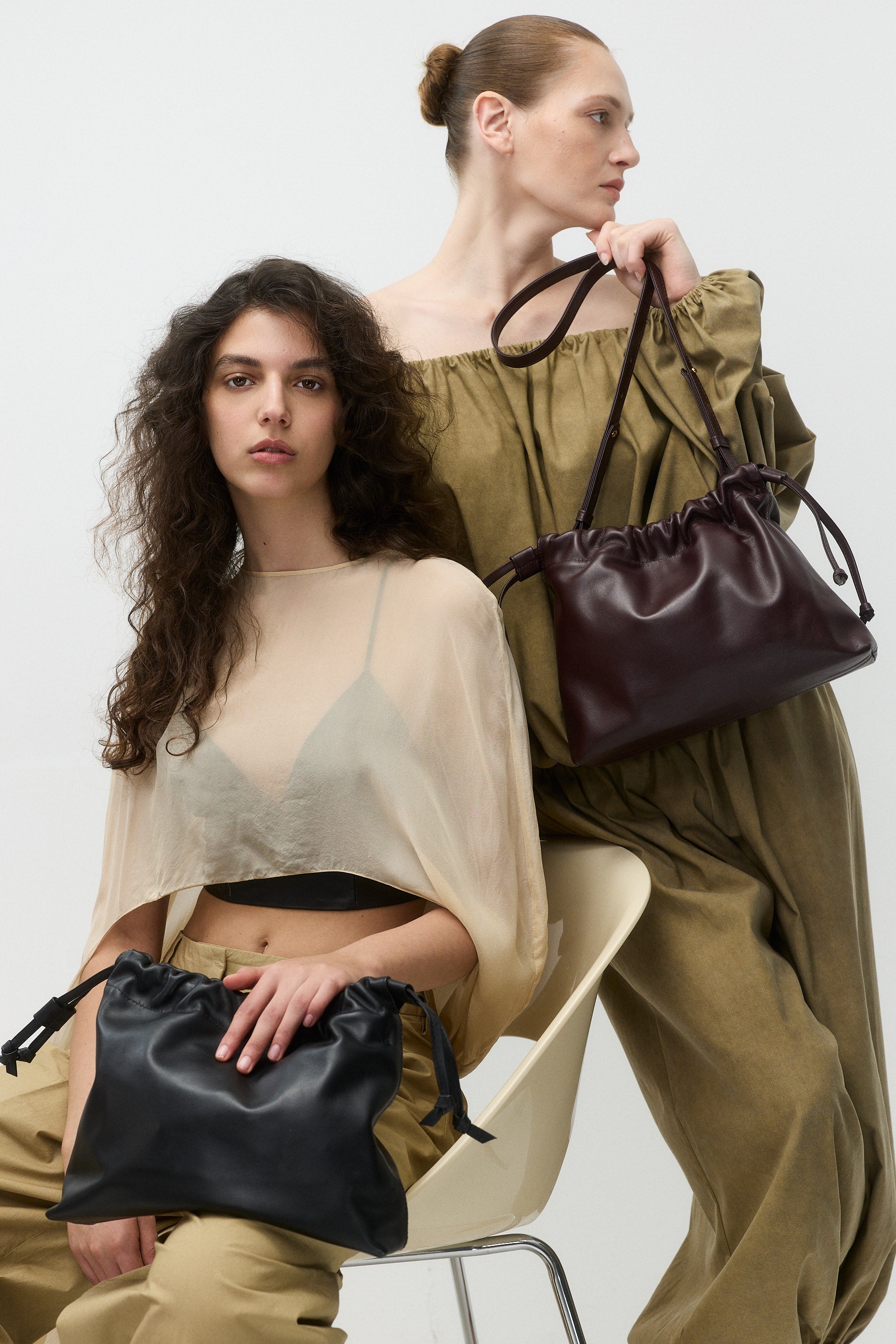 Two women holding the asisi medium handbag against a white background